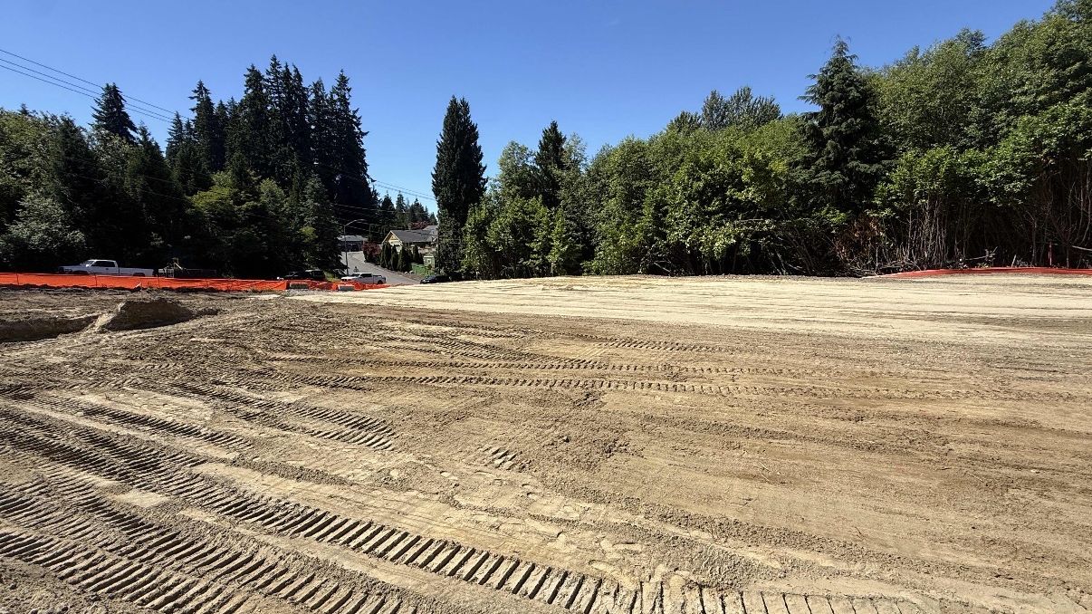 Excavator and trucks preparing a commercial site pad